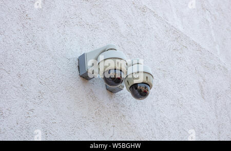 Security monitoring cameras CCTV system, outdoors on a white color building facade wall. Safety, privacy concept. Stock Photo