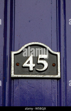 House number 45 with the forty five on a sign on a dark purple door Stock Photo