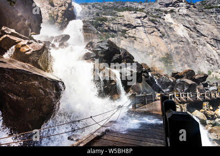 High debit Wapama Falls flowing over the footbridge and creating hazardous conditions for crossing; Hetch Hetchy Reservoir area, Yosemite National Par Stock Photo