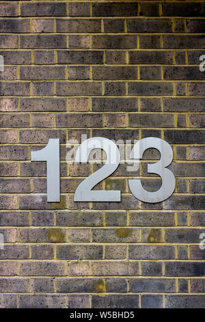 House number 123 on a yellow brick wall Stock Photo