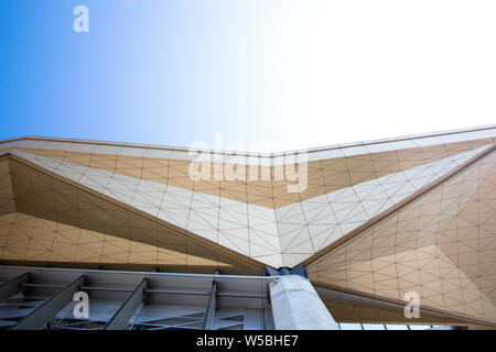 An architectural construction from glass and metal. Beautiful city building of the correct form against the background of the solar and blue sky. Stock Photo