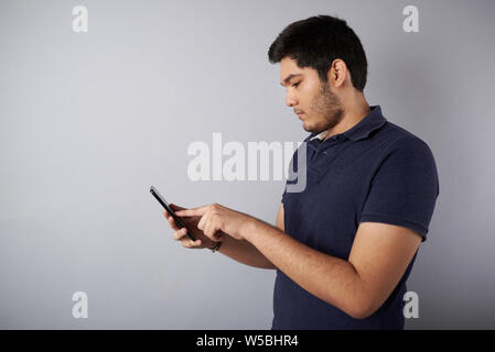 Young man touch smartphone profile view isolated on gray background Stock Photo
