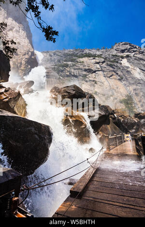 High debit Wapama Falls flowing over the footbridge and creating hazardous conditions for crossing; Hetch Hetchy Reservoir area, Yosemite National Par Stock Photo