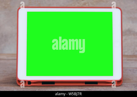 Mockup image of  White tablet pc with blank green desktop screen on wooden table Stock Photo