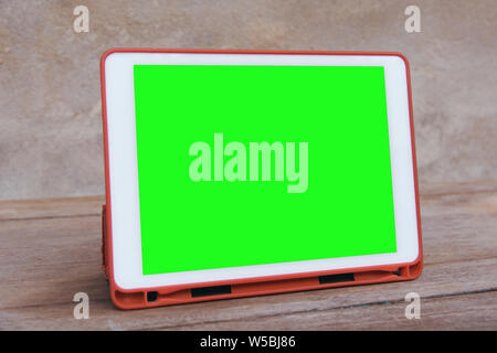 Mockup image of  White tablet pc with blank green desktop screen on wooden table Stock Photo