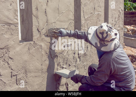 Construction workers plastering building wall using cement plaster Stock Photo