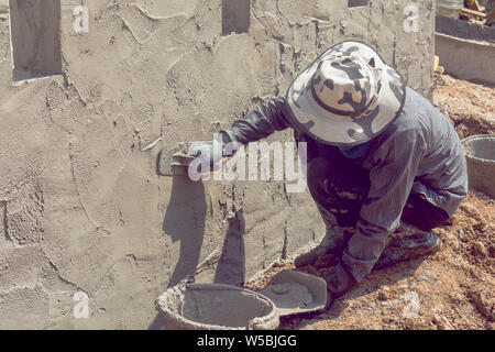 Construction workers plastering building wall using cement plaster Stock Photo