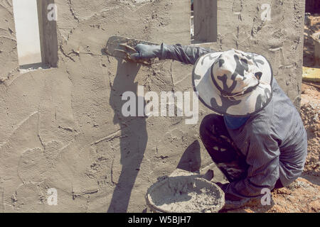 Construction workers plastering building wall using cement plaster Stock Photo