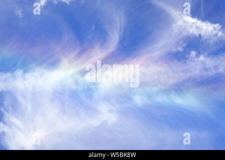 Cloud iridescence or irisation visible on the surface of white cirrus clouds; blue sky background Stock Photo
