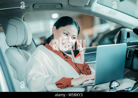 Smiling woman talking on her phone in a parked car. Stock Photo