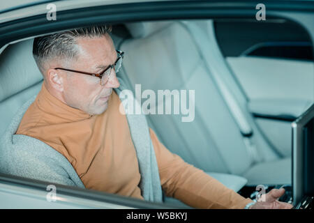 Serious man sitting on the backseat of the car. Stock Photo