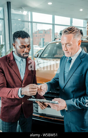 Man concluding a contract bying new car. Stock Photo