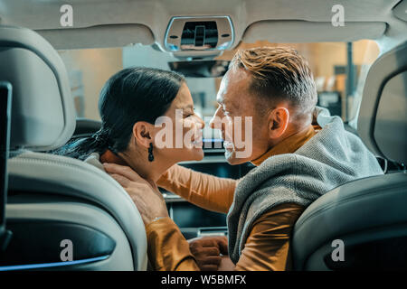 Husband and wife smiling before kissing in the car. Stock Photo