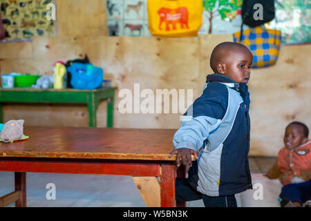 Nanyuki, Laikipia county, Kenya – June 10th, 2019: Young Kenyan child with back to table while at nursery side on to camera. Stock Photo