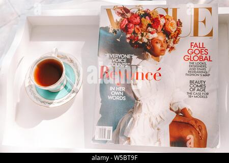 OTTAWA, CANADA - Feb 01, 2019: Morning Tea in Blue and GOld Vintage Tea Cup with Vogue Magazine Beyonce and White Tray Stock Photo