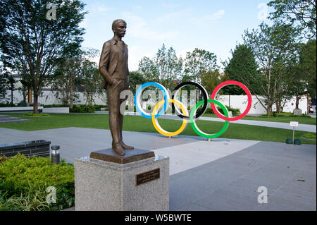 Tokyo, Japan - July 27, 2019: Olympic rings and statue of Pierre de Coubertin close to the Tokyo 2020 new national stadium