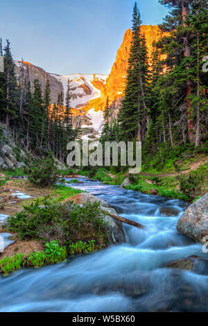 Fern Creek flows out of Odessa Lake below Notchtop Mountain and the Ptarmigan Pass seen through the forest in Rocky Mountain National Park, Colorado. Stock Photo