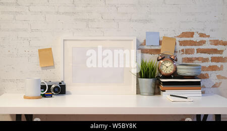 Mock up frame with vintage camera and other office supplies with old brick wall background Stock Photo