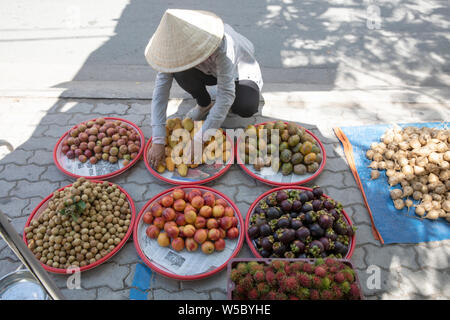 A woman arranging her fruit and vegetable produce for sale on the street in Ho Chi Minh City (Saigon) Vietnam Stock Photo