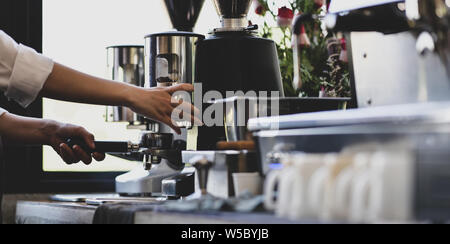 Close-up view of barista hand's making coffee with coffee maker machine in comfortable cafe Stock Photo