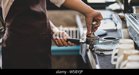 Close-up view of young professional female barista making coffee with coffee maker machine Stock Photo