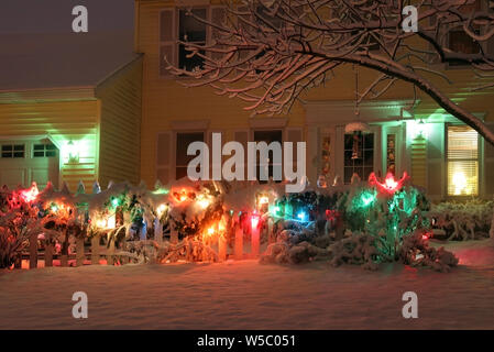 Front yard of the private house covered by snow and decorated for winter holiday season glowing in the night. Christmas and New Year background. Stock Photo