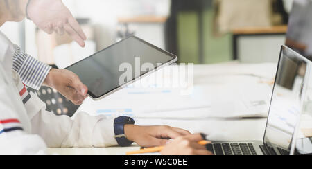 Young successful designers team brainstorming their upcoming project while working on tablet computer Stock Photo