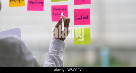 UI UX designer collecting any idea and stick it on the glass window Stock Photo