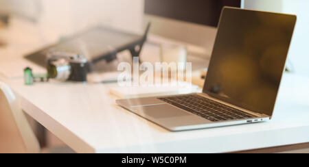 Laptop on modern white table with abstract blurred background Stock Photo