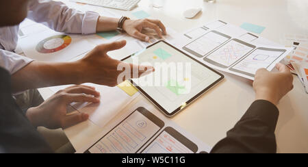 UX Designer team sketch mobile app developer outlines an app on tablet for web mobile smart phone Stock Photo