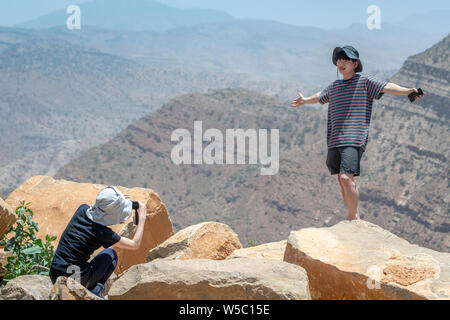 Tourist stand on tops of rocks and poses for photo on cliff in Danakil Depression ,  Ethiopia Stock Photo