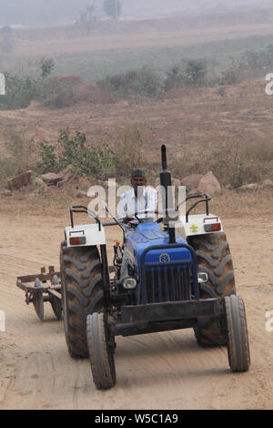 Farmer driving a tractor on a road Stock Photo