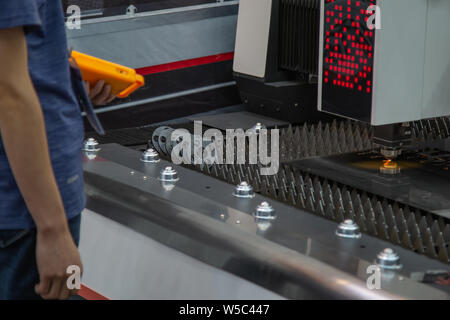 Industry worker operating laser cutting machine cutting metal sheet Stock Photo