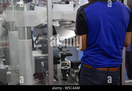 Worker using laptop to operate automation assembly robot in automotive industry Stock Photo
