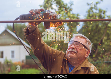 A man in safety glasses cuts metal with a special circular 