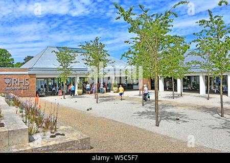 RHS Wisley people walk toward new modern welcome building Royal Horticultural Society Gardens passing tree planting on gravel path Surrey England UK Stock Photo