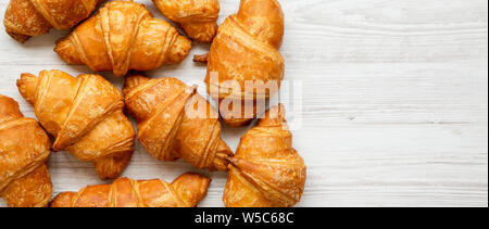 Freshly baked golden croissants on a white wooden background, top view. Space for text. Stock Photo