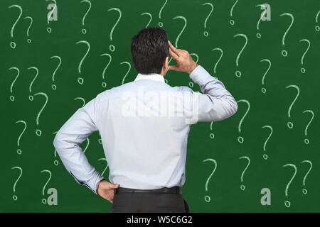 Businessman looking at question marks Stock Photo