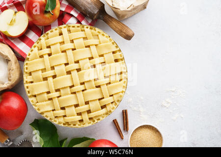 Making apple pie with lattice top. Raw unbaked apple pie with tools and ingredients for cooking. Stock Photo
