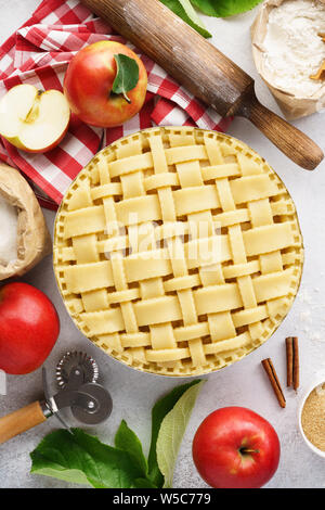 Making apple pie with lattice top. Raw unbaked apple pie with tools and ingredients for cooking. Stock Photo