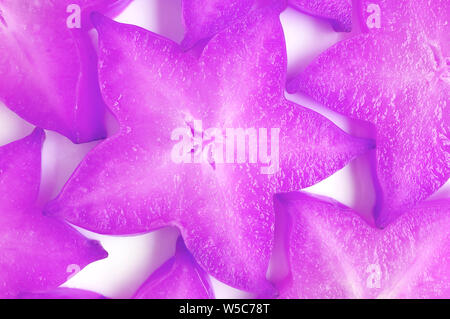 Top View of Sliced Fresh Star Fruits in Surreal Pop Art Styled Purple Colored for Background Stock Photo