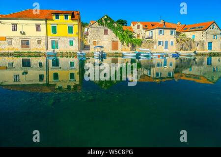 Fantastic travel and vacation location. Mediterranean old fishing and touristic village with stone houses reflected on the sea. Moored fishing boats i Stock Photo