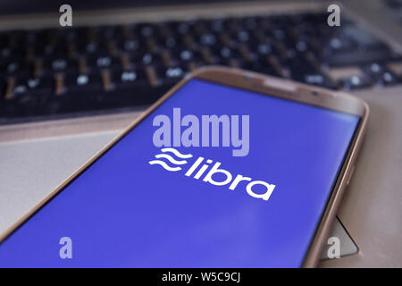 Facebook Cryptocurrency Libra concept with cellphone with Libra and Facebook logo on bue mobile phone screen in front Stock Photo