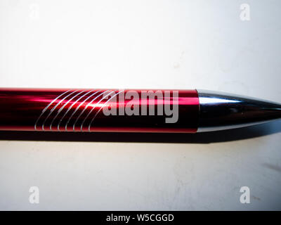 Cool background - macro of a metallic red pen with some white lines on it, transition from dark to bright Stock Photo