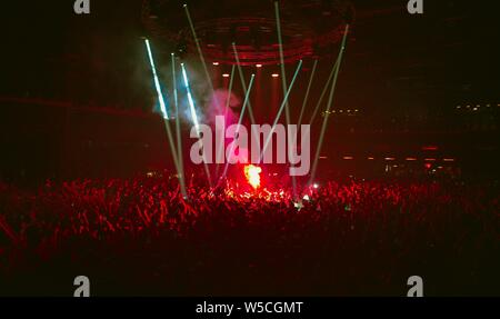 Group of excited music fans burn red fire torches on dance floor indoor.Dangerous fireworks on musical festival.Youth lifestyle and entertainment even Stock Photo