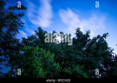 Blue sky with the bright moon in the middle and the clouds moving (photo in motion), Romania Stock Photo