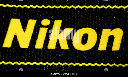 Macro of the Nikon logo written on a textile camera strap (the background texture is the material of the strap) Stock Photo