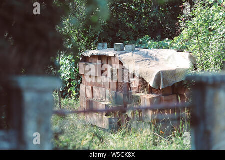 Details of a pile of stacked clay bricks with holes in a courtyard in a rural area Stock Photo
