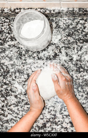 Top view of hands chef preparing a big ball of dough with flour on kitchen marble board. Preparing and kneading dough to cooking bread or pizza. Stock Photo