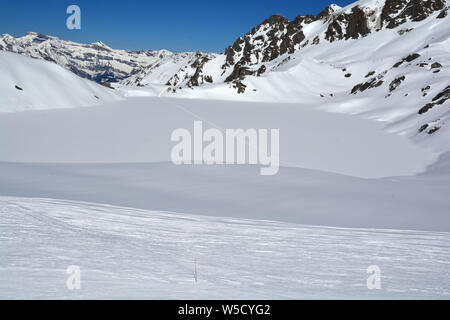 ski tracks cross a frozen lake in the mountains in Switzerland on a beautiful sunny day Stock Photo